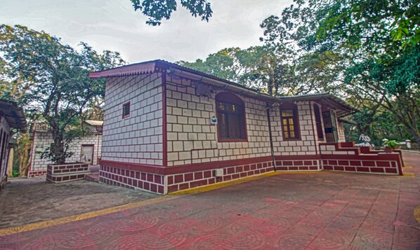 A small, single-story building with a tiled exterior and a red and white trim. - Treebo Shalimar In The Forest (Karjat)