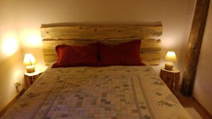 A bed with a quilt, two red pillows, and two bedside lamps on wooden nightstands. - "La Bergerie "Gîte at the end of the world. La Valbonnette (Barrême)