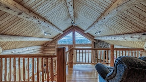 Eine Holzhütte mit Schrägdach, einem Balkon mit Geländer und Blick auf einen See.