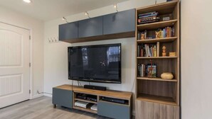 En stue med et fladskærms-tv, indbyggede hylder og et træunderholdningsmøbel.