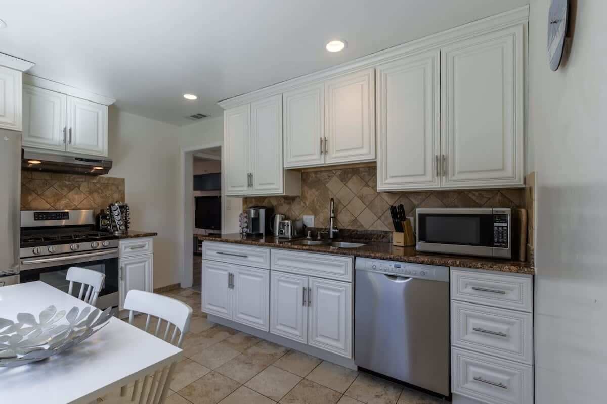 Una cocina moderna con armarios blancos, electrodomésticos de acero inoxidable y salpicadero de azulejos.