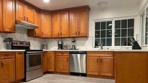 Una cocina con gabinetes de madera, electrodomésticos de acero inoxidable y un ventanal.