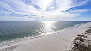 A beach with a clear sky and sunlight reflecting off the water. - Seawind 1705 by Liquid Life (Gulf Shores)