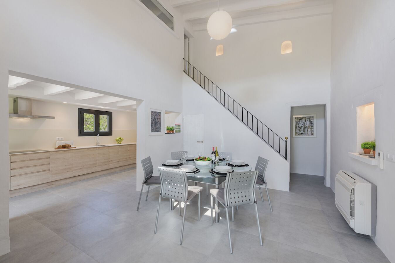 Une cuisine moderne avec un coin repas, un escalier et une vue sur l’extérieur.