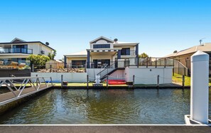 A waterfront property with a dock, a staircase leading to a covered area, and a pool.