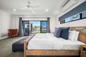 Een slaapkamer met een bed, een stoel, een plafondventilator en uitzicht op het omliggende landschap.