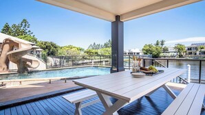 Un espace aménagé au bord de la piscine, avec une table et des bancs, un toboggan aquatique et une vue sur les environs.