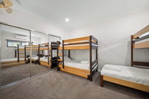 Ein Zimmer mit Etagenbetten, einem Spiegel und einem Deckenventilator.