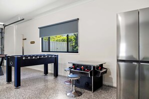 Une cuisine moderne équipée d’un baby-foot, d’un petit coin bar et d’un grand réfrigérateur.