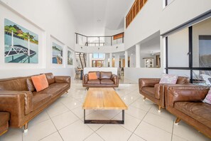 Un vaste espace de vie agrémenté de canapés en cuir, d’une table basse en bois et d’œuvres d’art accrochées aux murs.