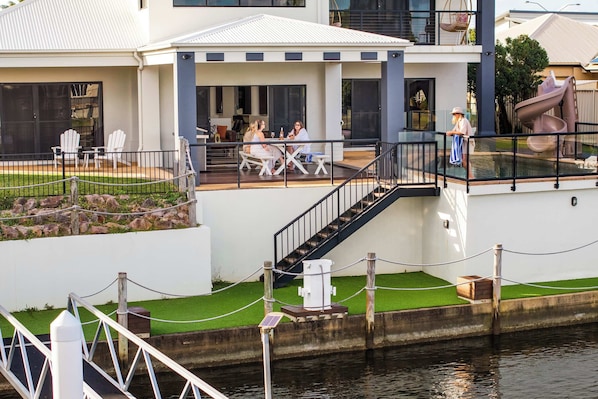 Une maison moderne dotée d’un patio couvert, d’un espace salon extérieur et d’un toboggan.