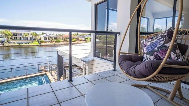 Un balcon donnant sur une piscine et un bâtiment situé de l’autre côté de l’eau.