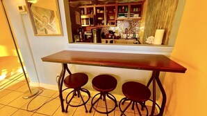 A bar area with a wooden table and three stools, a mirror, and kitchen cabinets above. - Wonderful oceanview condo, 3 bedrms, near the beach (Myrtle Beach)