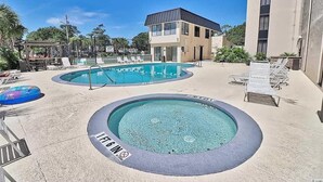 A pool area with a hot tub, lounge chairs, and a building with a modern design. - Wonderful oceanview condo, 3 bedrms, near the beach (Myrtle Beach)