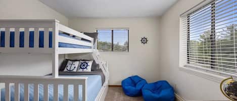 A room with bunk beds, a desk, a globe, and a window with blinds.