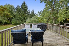 Eine Holzterrasse mit Tisch und Stühlen, umgeben von Bäumen.