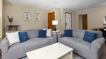 Ein Wohnzimmer mit zwei grauen Sofas, einem weißen Couchtisch und einer blauen Lampe.