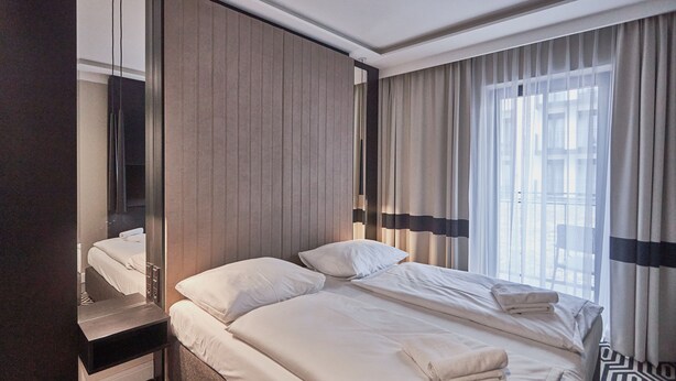 Een hotelkamer met een groot bed, een nachtkastje, een spiegel en een raam met gordijnen.