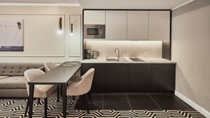 Een moderne keuken met een ingebouwde magnetron, een spoelbak en een eethoek met een tafel en stoelen.