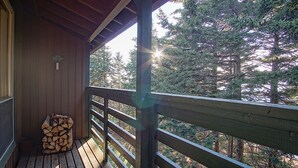 Een houten terras met een balustrade met uitzicht op een bos.
