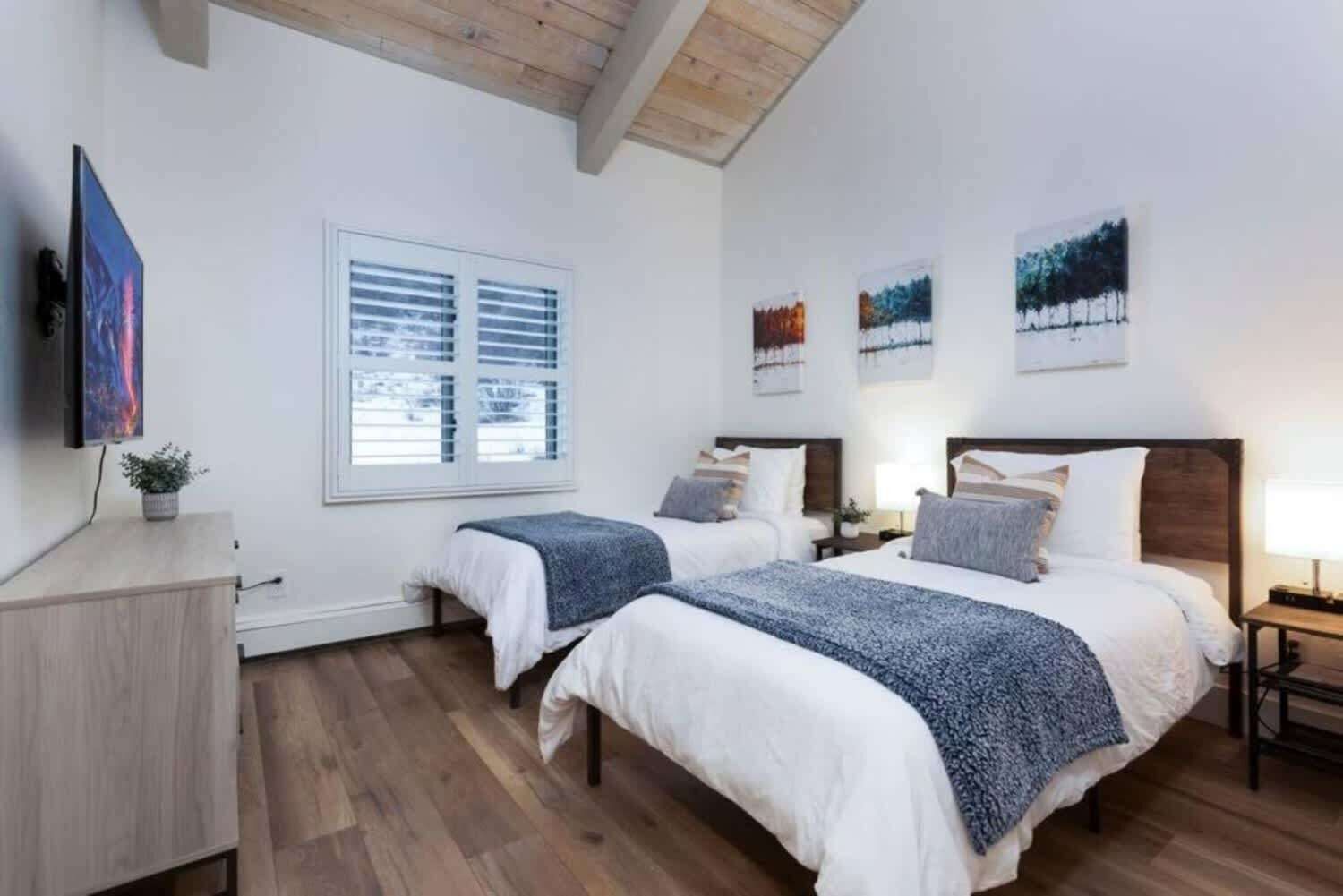 Une chambre d’hôtel avec deux lits, une télévision et des œuvres d’art accrochées aux murs.