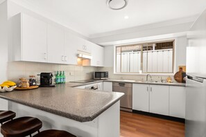 A modern kitchen with white cabinets, a granite countertop, a built-in microwave, and a dishwasher.