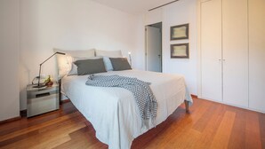 Ein Schlafzimmer mit Bett, Nachttisch, Lampe und einem Kunstwerk an der Wand.