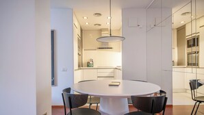 Ein moderner Essbereich mit einem runden Tisch, vier Stühlen und Pendelleuchten.