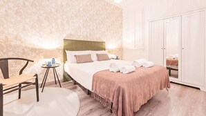 Quarto de hotel com cama, uma cadeira, tapete redondo e guarda-roupa.
