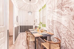 A dining area with a long table, chairs, and a peacock-themed wallpaper. - Sweett | Rocafort 302 (Barcelona)