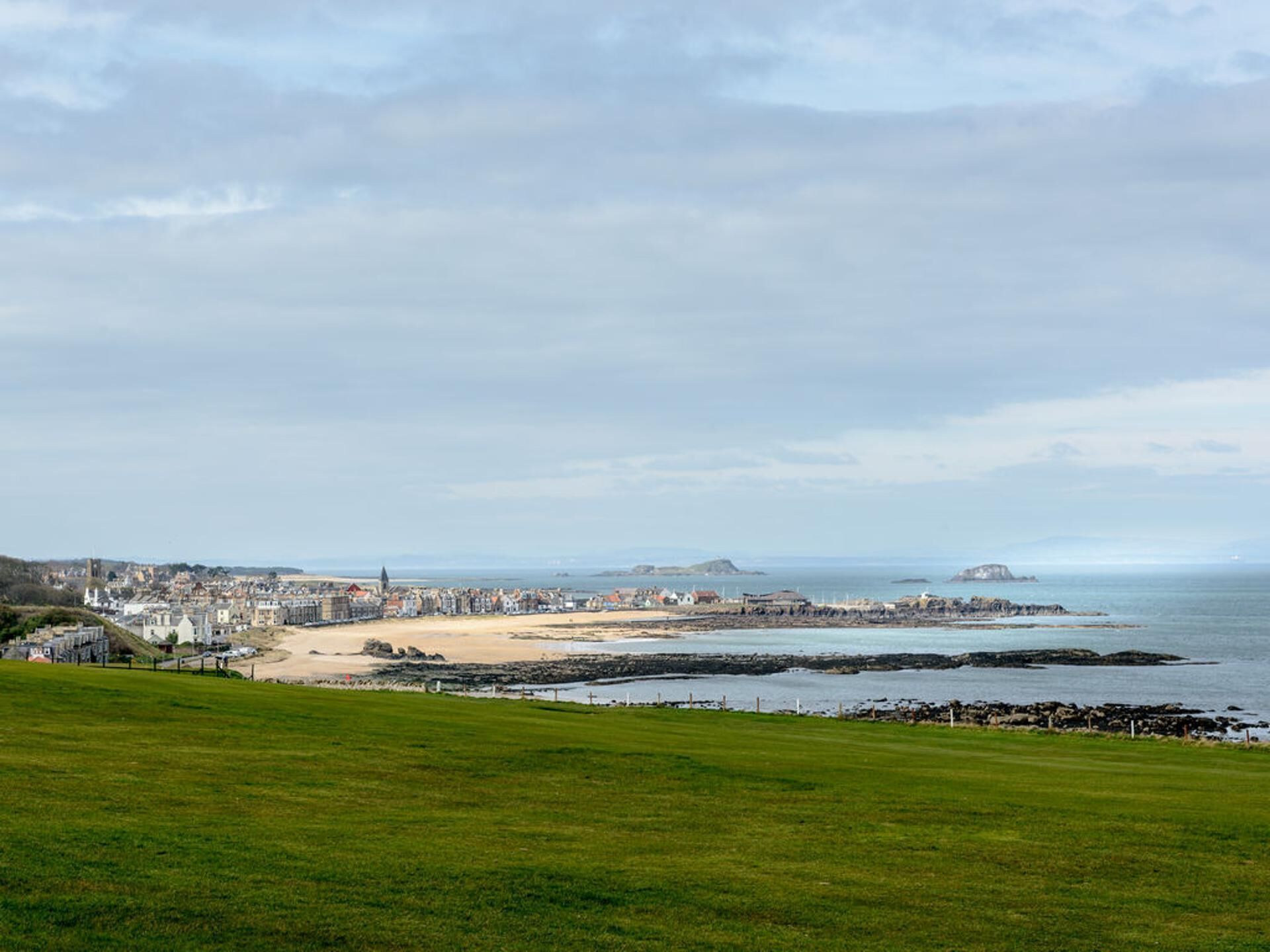 A coastal town with a beach, rocky shoreline, and buildings along the coast.