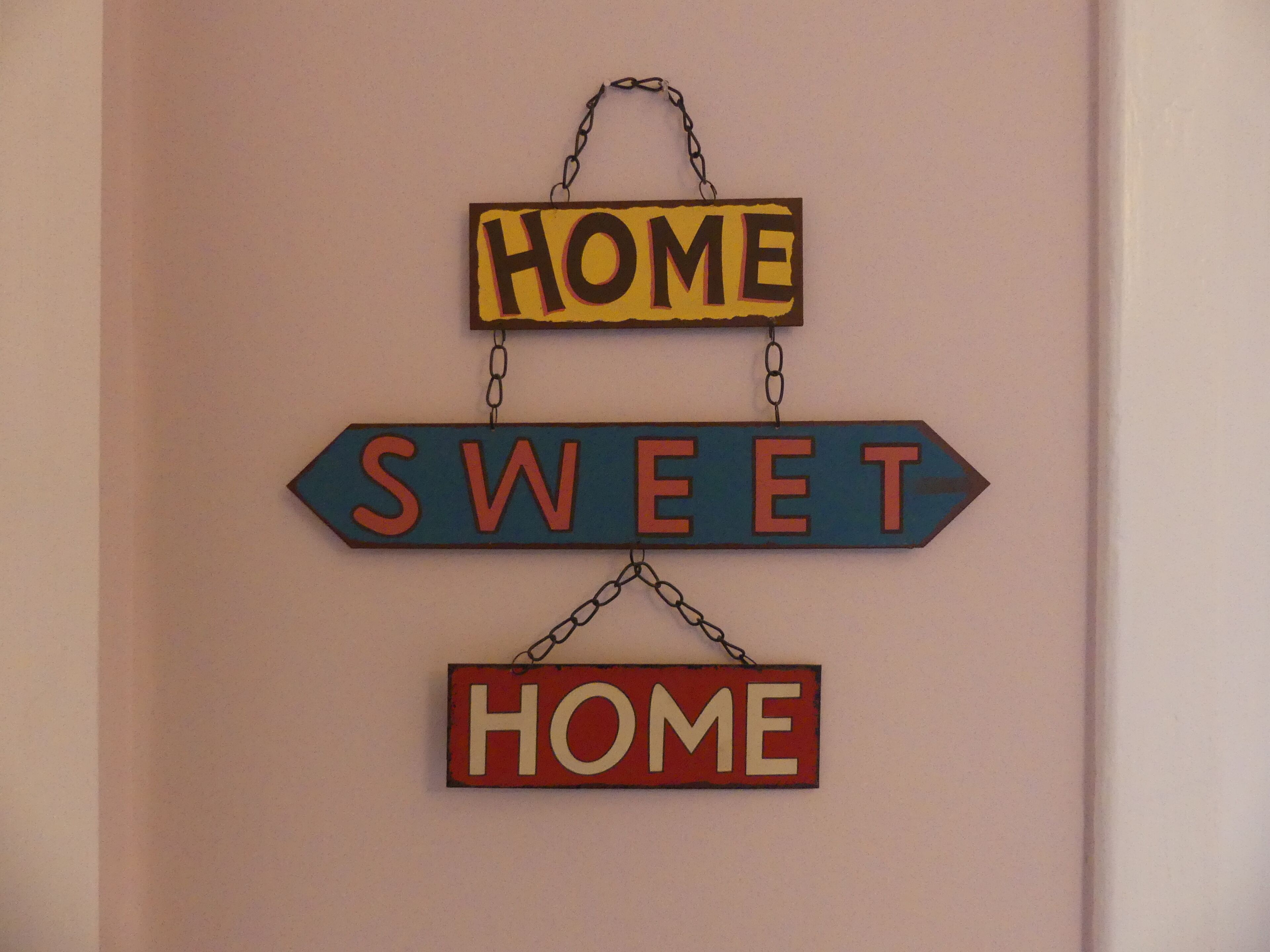 Un letrero en la pared con las palabras 'HOME' y 'SWEET' en diferentes colores y estilos.