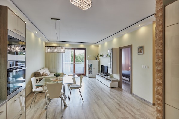 A modern kitchen with a dining area, built-in appliances, and a large window providing natural light.