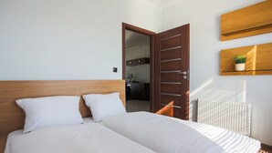 A hotel room with a double bed, a wooden headboard, a small potted plant on a shelf, and a radiator. - Apartamenty Swinoujscie-Wojska Polskiego (Swinoujscie)