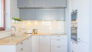 A modern kitchen with white cabinets, a wooden countertop, and built-in appliances. - Apartamenty Swinoujscie-Wojska Polskiego (Swinoujscie)