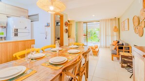 A modern kitchen with a refrigerator, microwave, and dining area with yellow chairs and a wooden table set for a meal. - IT29 Excelente ap 3 Quartos 50m da Praia (Camaçari)