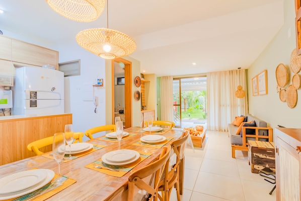 A modern kitchen with a refrigerator, microwave, and dining area with yellow chairs and a wooden table set for a meal.