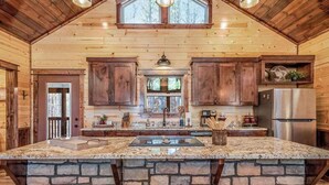 Une cuisine spacieuse dotée d’un grand îlot central, d’un comptoir en pierre et de tabourets de bar en bois.