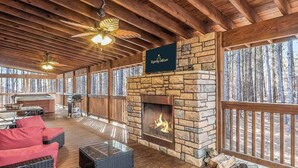 Un vaste espace extérieur doté d’une cheminée en pierre, d’une terrasse en bois et de mobilier d’extérieur rouge.