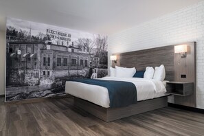 A modern bedroom with a bed, headboard, nightstands, and a mural on the wall. - Hôtel l'Étape (Mont-Laurier)