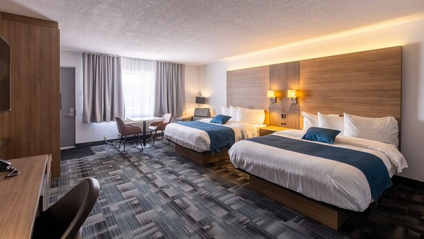 Habitación de hotel con dos camas, un escritorio y una silla.