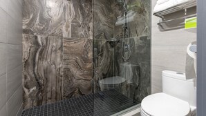 Un baño moderno con ducha de vidrio, inodoro blanco y pared de mármol.