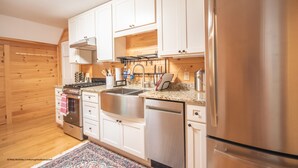 Une cuisine moderne dotée d’appareils électroménagers en acier inoxydable, de meubles blancs et d’un plancher en bois.