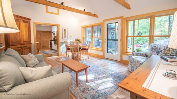 Un salon spacieux doté d’un plafond en bois, d’un canapé, d’une table basse et d’un coin repas avec des chaises et une table.