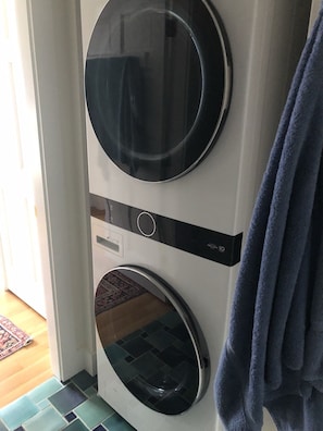 Eine Waschmaschine mit Frontlader und ein Trockner in einem Waschraum, der einen Teppich mit Muster aufweist.