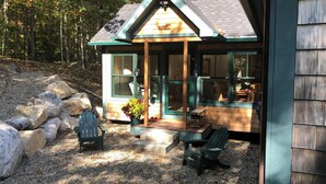 Une cabane avec une véranda, une chaise et une plante en pot.