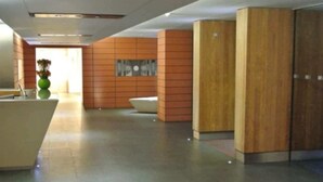 Un hall d’entrée moderne avec un comptoir d’accueil, un vase vert et un grand meuble en bois.
