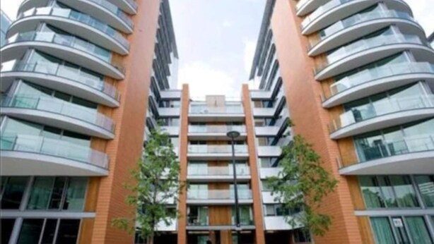 Un immeuble moderne à plusieurs étages, doté d’une entrée centrale, de grandes fenêtres et d’une façade symétrique.