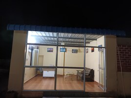 Una habitación con un ventanal grande, suelo de madera, un sofá, una silla y una pequeña mesa.