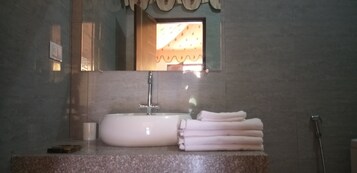 Un baño con un lavamanos blanco, un espejo y un perchero para toallas.